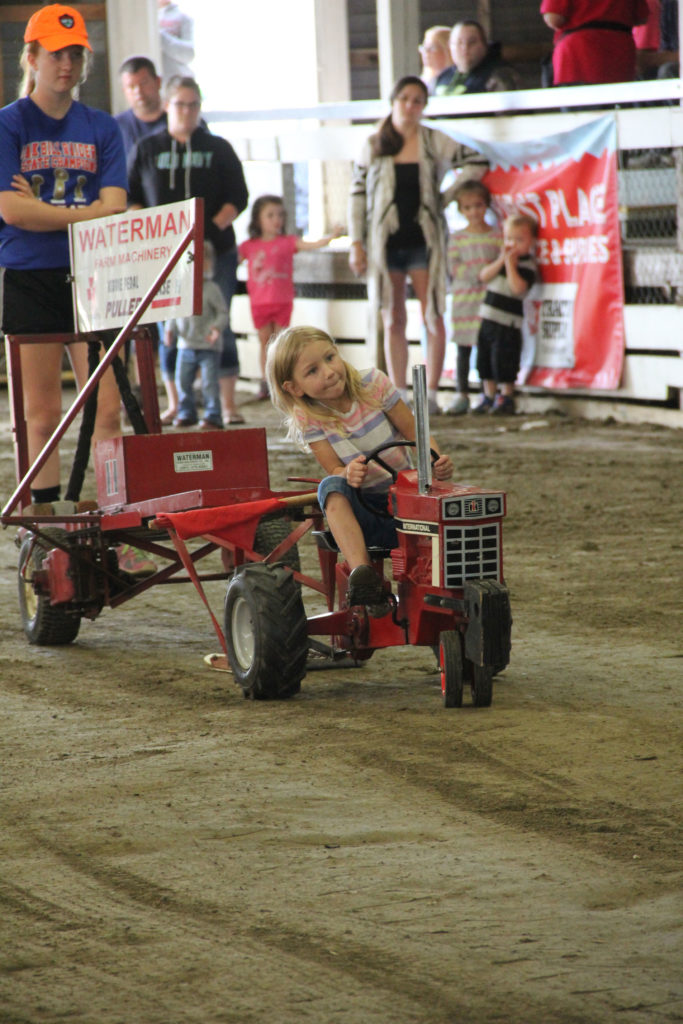 A young competitor pedals to victory in the kiddie tractor pull