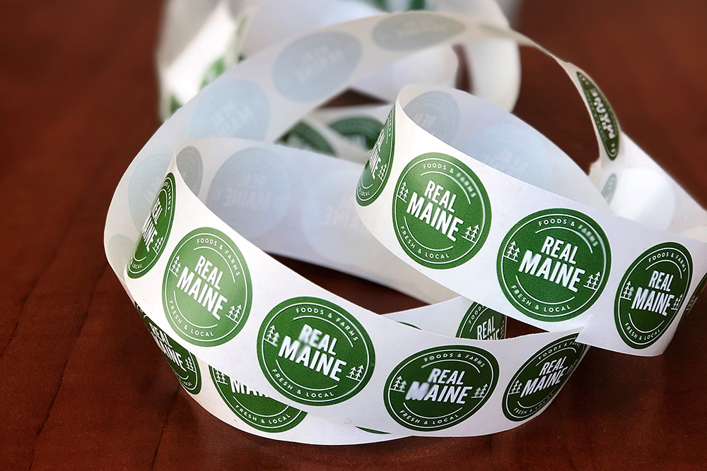 A roll of stickers showing the Real Maine logo