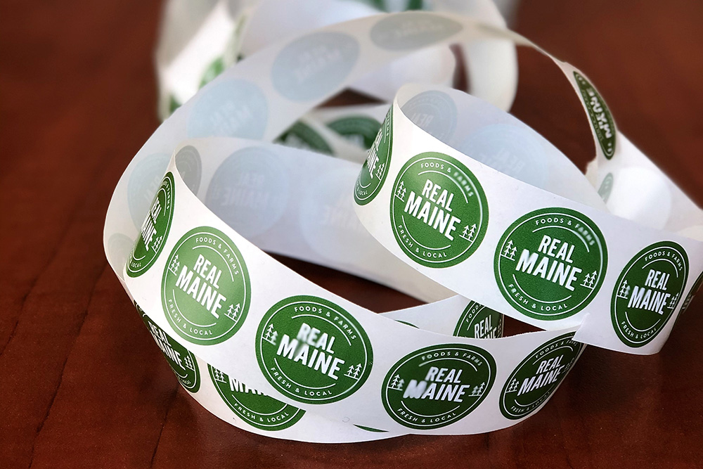 A roll of stickers showing the Real Maine logo