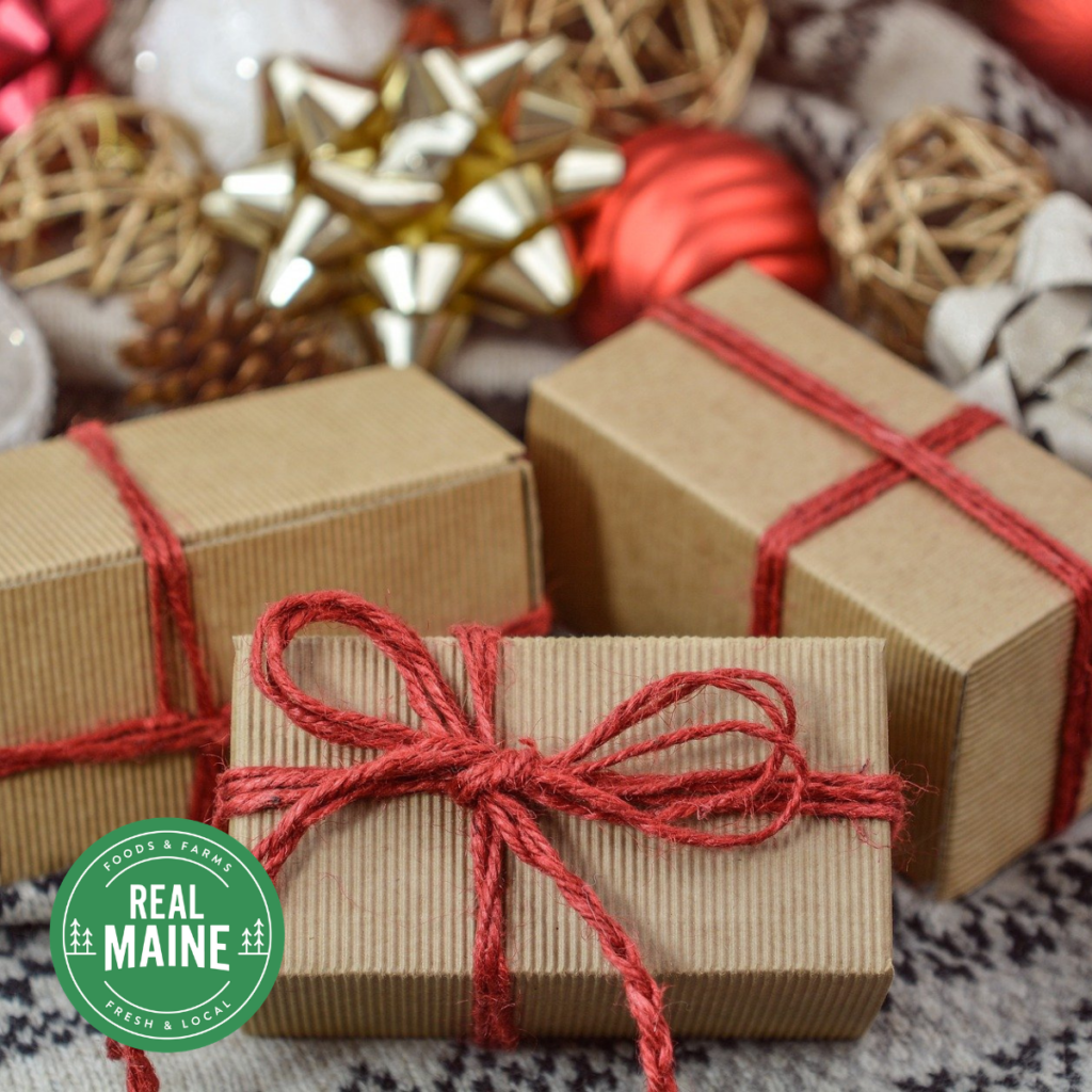 3 wrapped gifts with red twine bows and festive descorations in the background